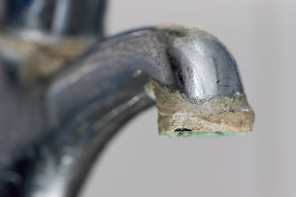 water faucet showing limescale buildup from hard water