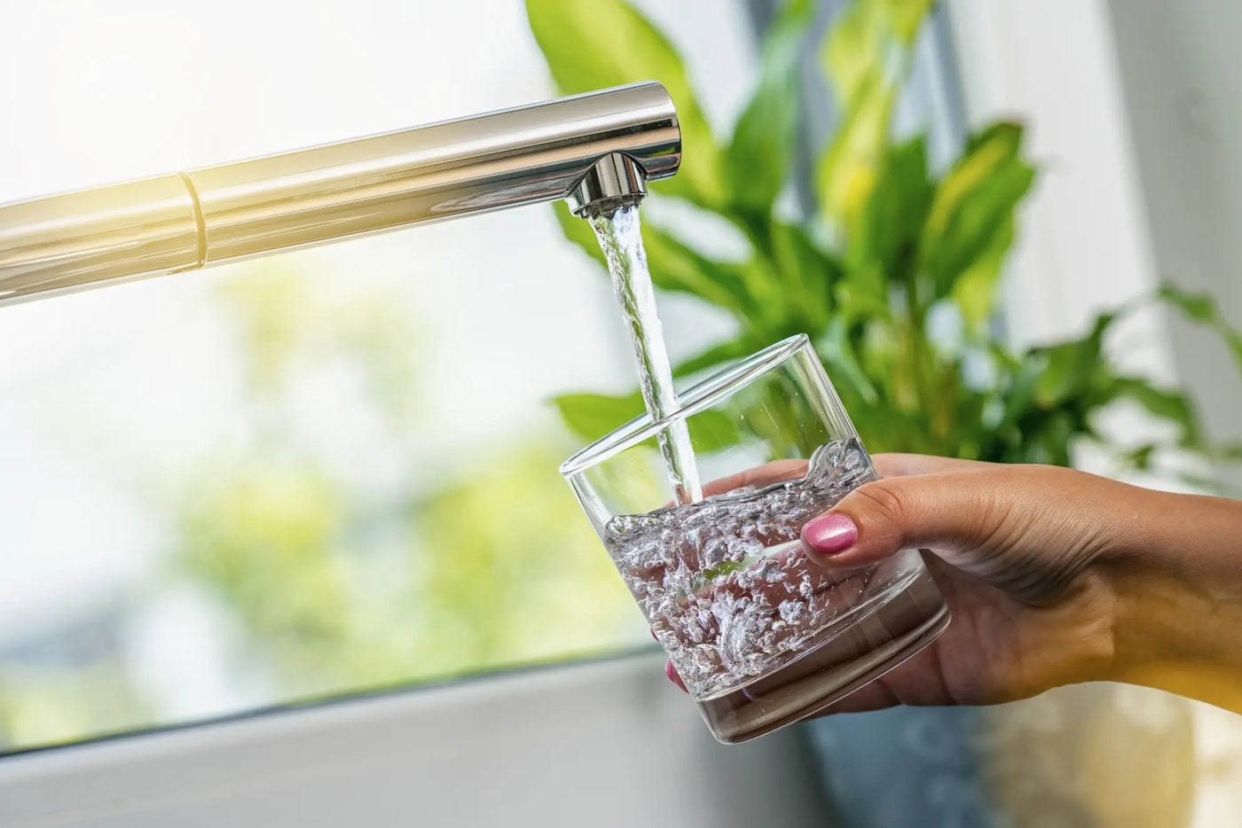 Clear water filling a drinking glass at a kitchen faucet, the fresh water a well sulfur filter restores