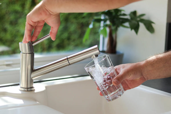Filling a drinking glass with clean water from a kitchen faucet