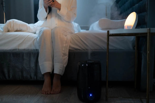 Cool mist humidifier running beside a bed in a home bedroom
