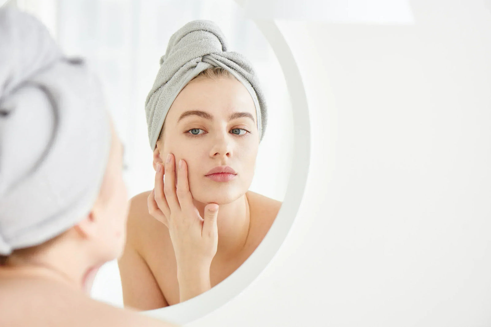 woman looking at her skin up close in a mirror