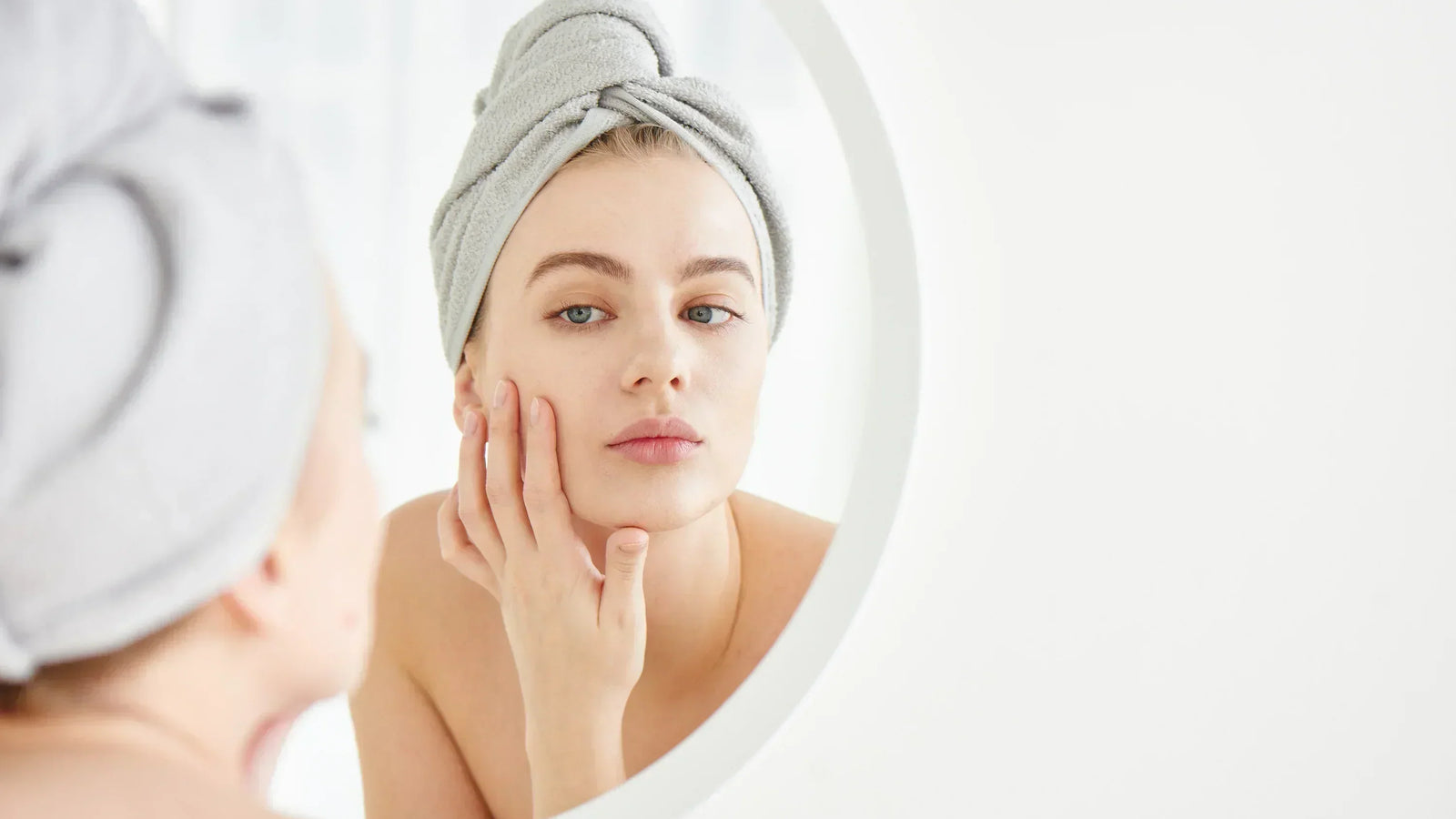 woman looking at her skin up close in a mirror