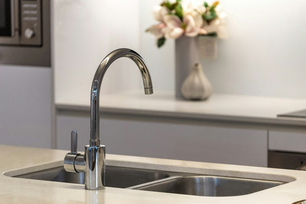 Modern residential kitchen sink with a chrome faucet and stainless steel basin, where dishwasher and reverse osmosis air gap connections are installed