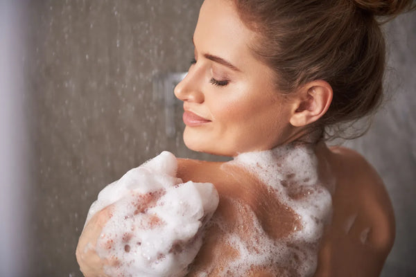 A woman in the shower with soap lather on her skin, the full clean-rinsing lather that softened water produces
