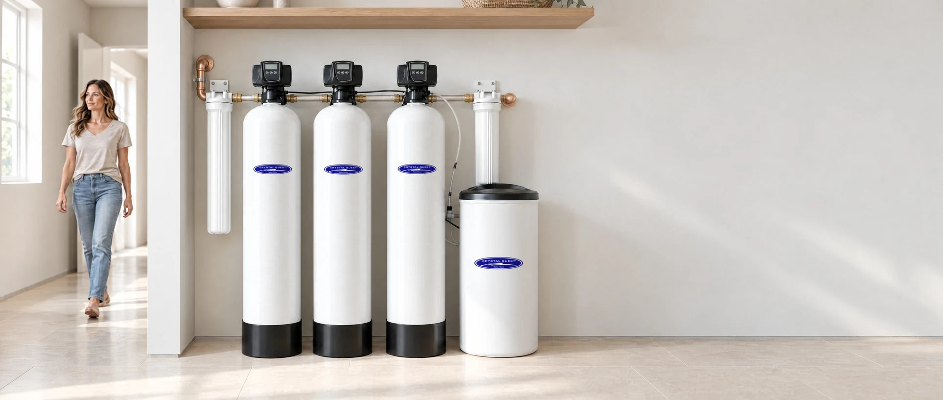 Complete Well Water System: three treatment tanks, a brine tank and two filter housings in an illustrative utility room, with a woman walking past