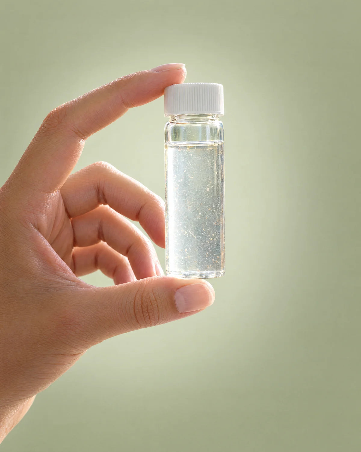 A hand holding a small water sample vial